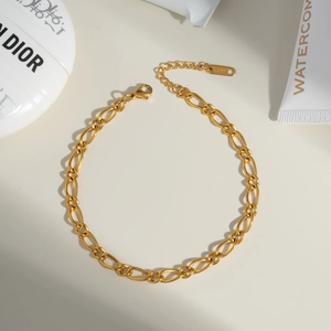 Minimalist golden stainless steel oval link anklet with lobster clasp on beige background