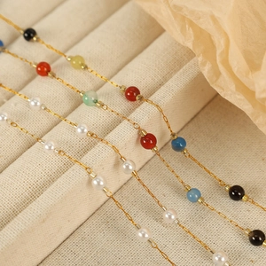 Minimalist gold chain necklace set with colorful beads on velvet display tray