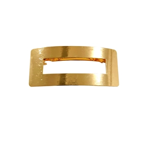 Detail shot of the brushed golden metallic texture on a hollow rectangular hair clip
