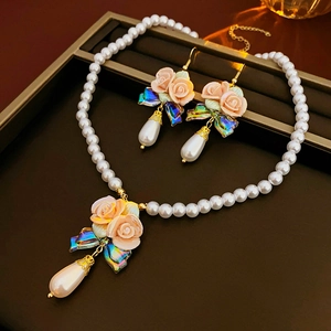 Detail of elegant pearl necklace and earring set with floral bow pendants in jewelry tray
