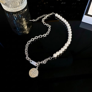 Elegant minimalist pearl and silver chain necklace with a round metal pendant on black