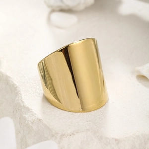 Macro shot of minimalist polished gold wide band ring on a natural stone surface