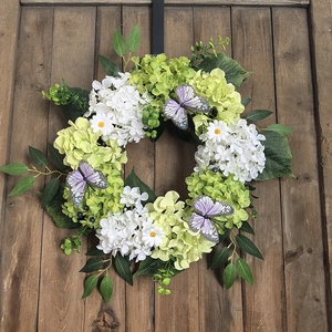 Detail of rustic autumn wreath with white hydrangeas and butterflies on a wooden door
