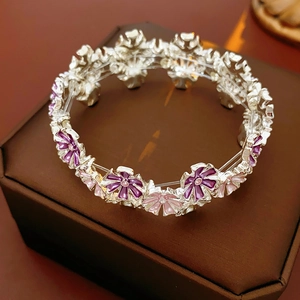 Detail eines elastischen Armbands mit lila und rosa Emailleblüten auf Schmuckbox