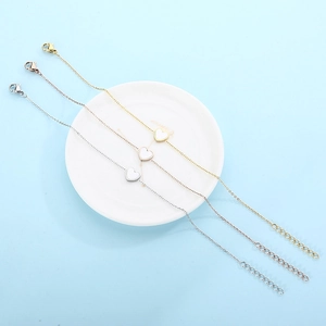 Detailed view of three heart pendant bracelets in gold, silver, and rose gold finishes