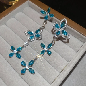 Macro shot of butterfly tassel earrings with blue flower gems and white crystals