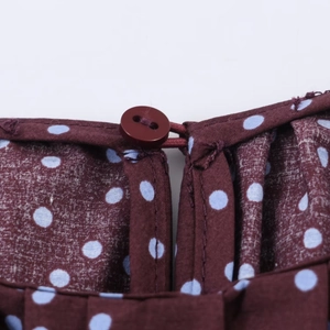 Close-up of the burgundy polka dot shirt collar with a button and elastic loop closure