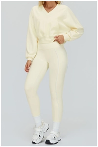 Full body view of light yellow hooded sweatshirt and matching high-waisted yoga leggings