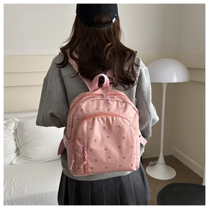 Detailed view of pink school backpack featuring delicate floral embroidery and nylon texture