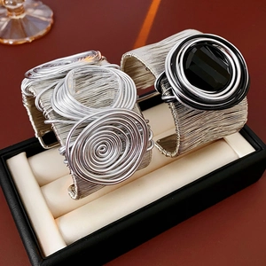 Detailed macro view of silver wire-wrapped cuff bracelets with black stone and ring accents