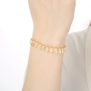 Detail of elegant gold drop bracelet with light pink beads on a model's wrist