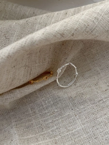 Detailed close-up of gold and silver heart rings with wavy texture on linen background