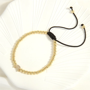 Detail of gold beaded bracelet with a sparkling crystal moon charm on a shell plate