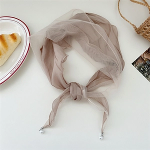 Detail of light brown lace scarf with pearl bead accents and knotted mesh texture