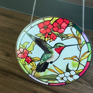 Macro detail of acrylic suncatcher featuring a colorful hummingbird and vibrant flowers
