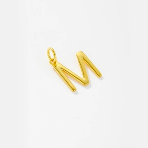 Macro shot of polished gold-plated letter M pendant with high-shine metallic finish