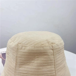 Gros plan du chapeau bob beige montrant la texture côtelée et la couture à double fil