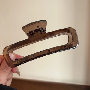 Detail view of large brown acetate hair claw clip with rectangle hollow design