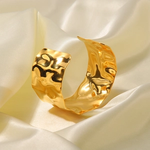 Macro detail of wide 18K gold plated steel cuff featuring unique hammered lava texture