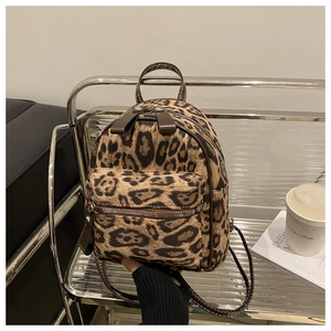 Detail view of mini leopard print backpack with front zipper pocket on metal shelf