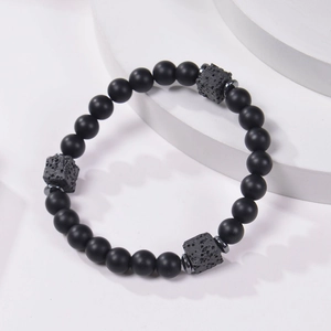Minimalist 8mm matte black stone and square lava rock strength bracelet on white podium