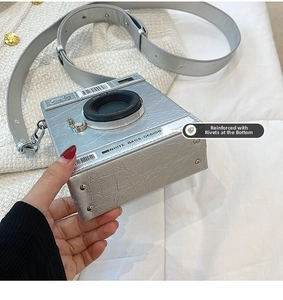 Détail du sac bandoulière argenté en forme d'appareil photo avec cuir texturé et rivets