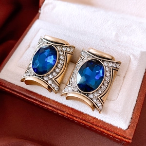 Detailed close-up of vintage oval blue gemstone earrings with crystal halo in gold finish