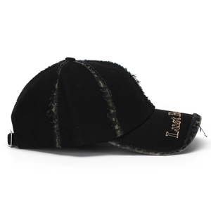 Detail of frayed edges and gold letter embroidery on a black vintage cotton baseball cap
