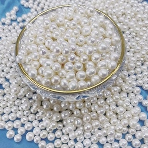 Macro shot of 6-7mm round white freshwater pearls in a gold-rimmed glass bowl on blue silk