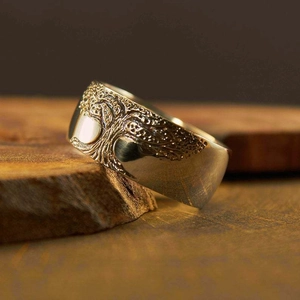 Silver vintage tree of life ring with embossed pattern on a rustic wooden texture