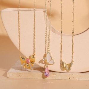 Detailed shot of gold butterfly necklaces with pink gems on a stone pedestal