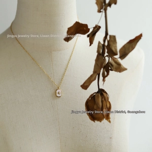 Close-up of a gold starburst necklace with a pink shell pendant on a fabric mannequin