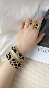 Detail of stylish leopard print bracelet set with gold edges and matching rings