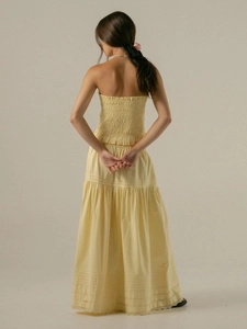 Detail of smocked back and layered A-line skirt with lace trim in pale yellow cotton