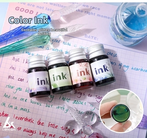 Detailed close-up of sparkling glitter ink bottles and spiral glass dip pens on vintage paper