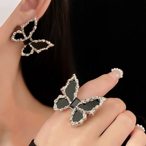 Close-up of elegant black butterfly earrings and ring set worn by a model