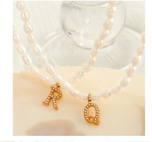 Macro view of gold-plated letter pendants R and Q on elegant pearl necklaces