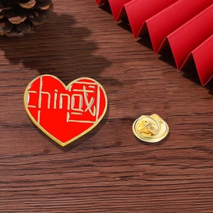 Detailed view of heart-shaped China flag enamel pin with gold edging on wooden background