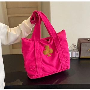 Close-up of pink canvas tote bag with yellow club-shaped patch and frayed edges detail