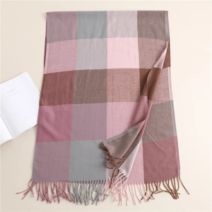 Close-up of soft plaid scarf with pink brown and grey tassels on a clean background