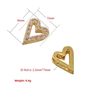 Macro detail of a gold heart charm with pink zircon inlay and dimensions 8mm x 7mm