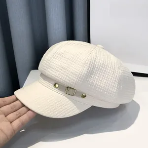 Close-up of white waffle texture newsboy cap with gold buckle and grey leather strap