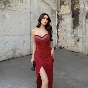 Detailed view of red satin evening gown featuring sparkling rhinestones and a high side slit