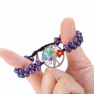 Detail of amethyst beads with a tree of life pendant on a black woven cord bracelet