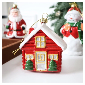 Close-up of a red Christmas house ornament with snow details and golden hanging loop