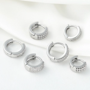 Elegant silver huggie hoop earrings with micro-paved cubic zirconia on white silk
