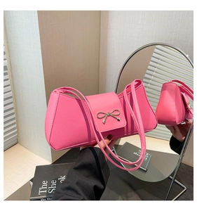 Detailed view of pink faux leather bag featuring a gold metal bow buckle and slim straps