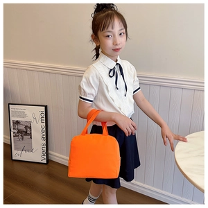 Orange insulated lunch bag with top handles held by child model in bright room