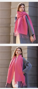 Close-up of pink cashmere-like scarf showing soft texture and fringe tassel detail