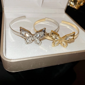 Close-up of gold and silver butterfly open bracelets with sparkling crystal inlay on display